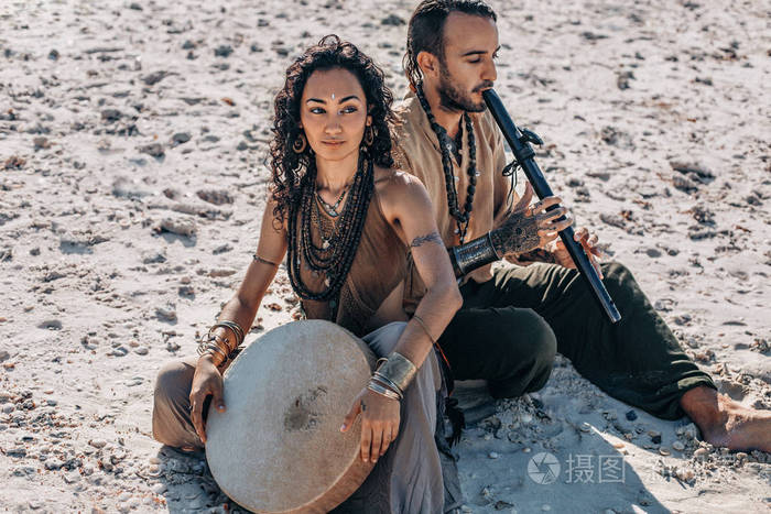 beautifulyoungcoupleplayingethnicalmusicwithshamandrums