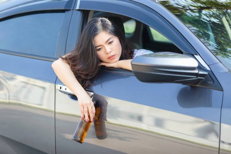 年轻的亚洲女人开车喝啤酒