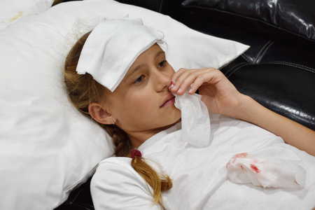 鼻血孩子流鼻血.头痛的女孩躺在床上.照片