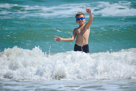 男孩在海浪上跳跃。快乐的海洋孩子。