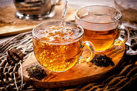 一大早在柳条桌上喝两杯红茶.清晨茶.倒茶的过程.照片