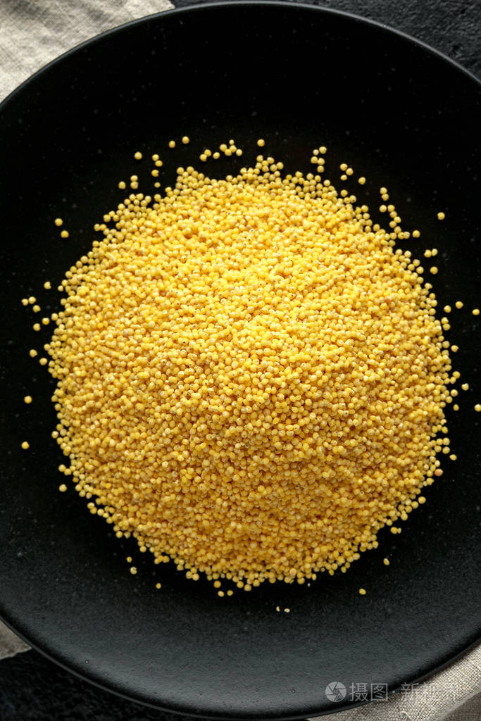 小米谷粒倒在黑盘子里有机概念