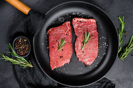 在平底锅里放生的牛里脊牛排。牛肉。黑色背景。俯视图