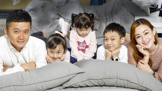 Parent Children father mother son daughter on bed posing happy 