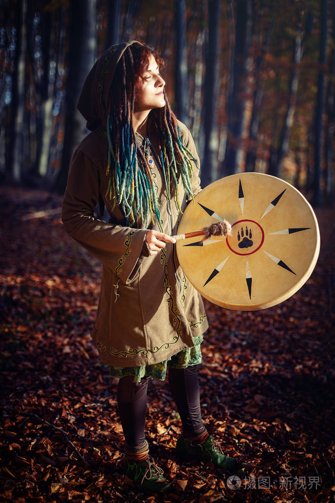 美丽的萨满教女孩在大自然中的萨满框架鼓.