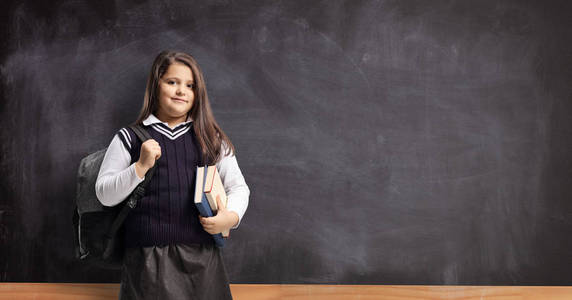 Schoolgirl in a uniform standing in front of a chalkboard 