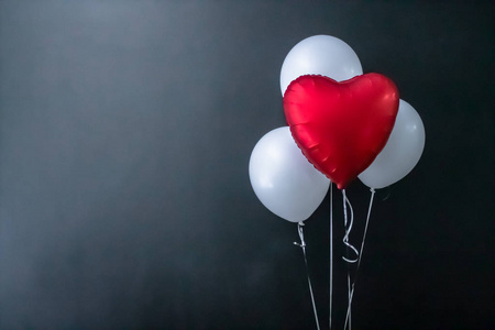 黑色背景上的红色心形气球和白色圆形气球。情人节，节日，爱情。