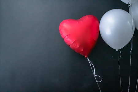 黑色背景上的红色心形气球和白色圆形气球。情人节，爱。