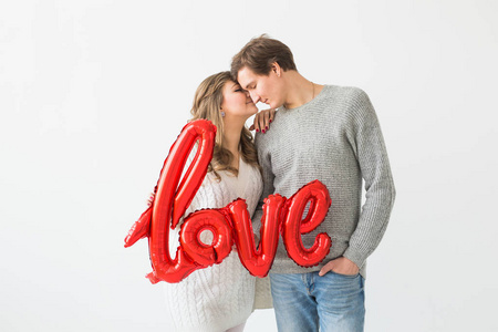 情人节，假日和礼物概念。幸福的年轻白人夫妇手持白色背景上的红色气球