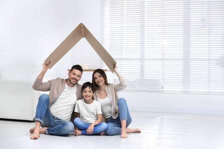 幸福的一家人坐在家里的硬纸板屋顶下。保险欺诈