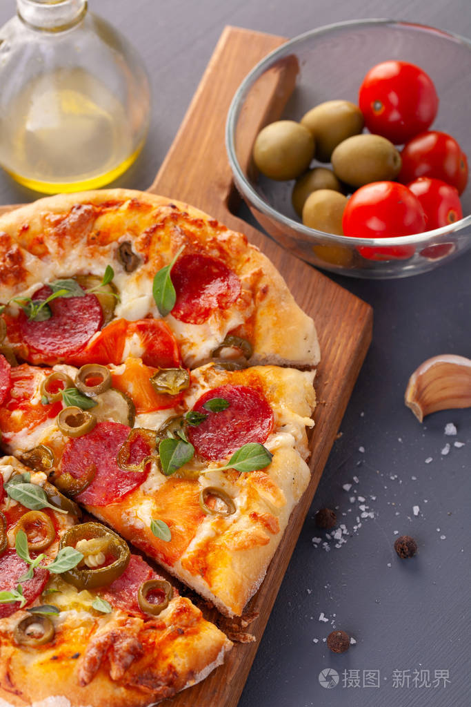 自制辣味香肠披萨和烹饪原料灰色木桌上的意大利香肠披萨