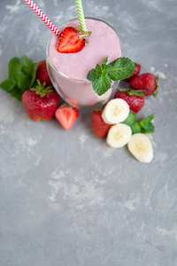 草莓和香蕉健康冰沙与新鲜草莓在玻璃装饰薄荷。