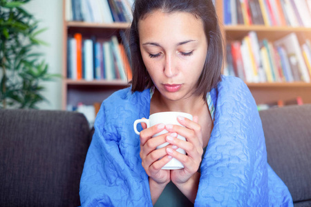 Sick woman covered by a blanket on the sofa with high fever and 