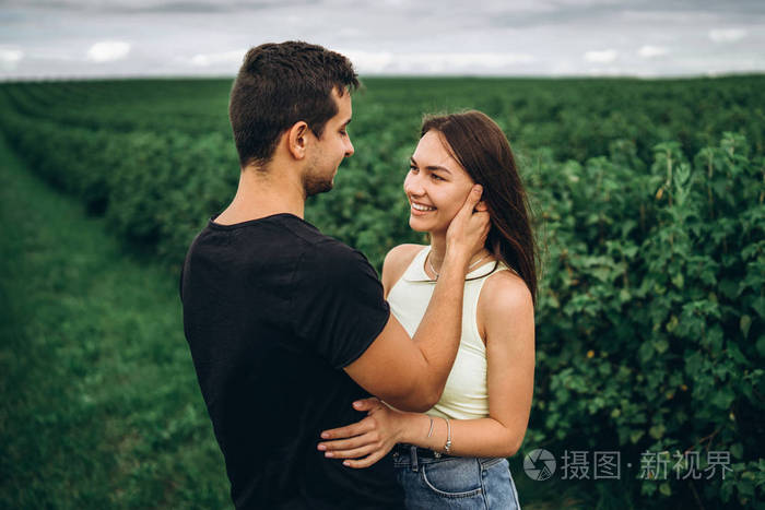 年轻的情侣在绿色背景下轻轻拥抱