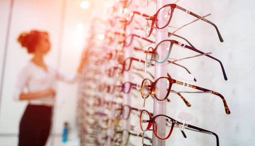 眼镜店的一排眼镜。眼镜店。戴着眼镜站在光学器材库里。女人选择眼镜。视力矫正。