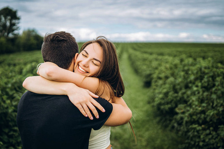 Cute young girl with long hair hugs her lover, smiling and with 