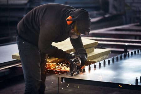 重工业工人用角磨机切割钢材