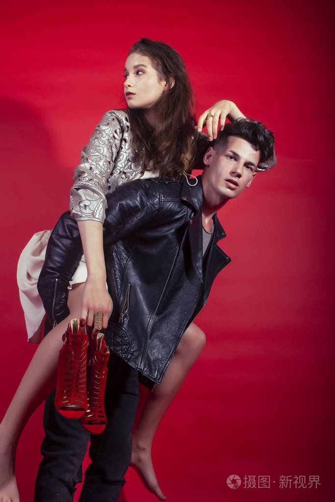 男女女在红色背景下手捧派对鞋摆造型,时尚风格让人眼前一亮照片-正版