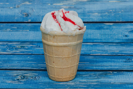 vanilla  cream with strawberry jam in a waffle cup on a blue 