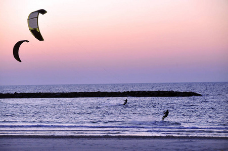 Kitesurfers surfing at sunset over the Mediterranean sea in Tel 