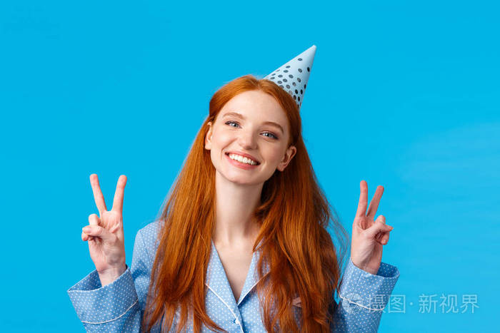 快乐快乐的红发女人戴着生日帽歪着头微笑着乐观庆祝