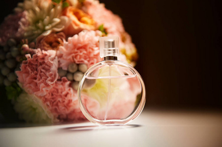 深色背景的圆形香水瓶，靠近粉红色的花束花。芳香疗法还有香水。