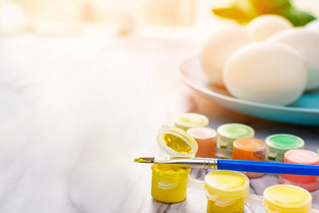 复活节概念在一个阳光明媚的早晨，在大理石桌上用刷子和一个带彩蛋的蓝色盘子画彩蛋