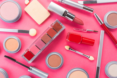 在粉红色的背景上，用不同的化妆品组成，顶视图。美容产品与时尚理念。