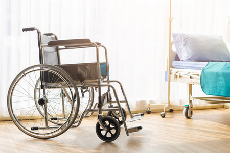 Empty wheelchair and bed in patient room, in hospital.