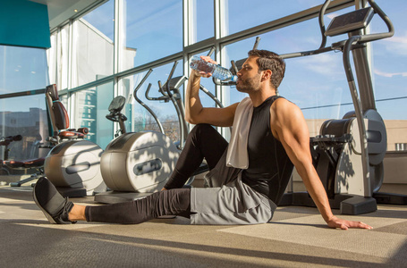  Handsome fit man drinking water in the gym