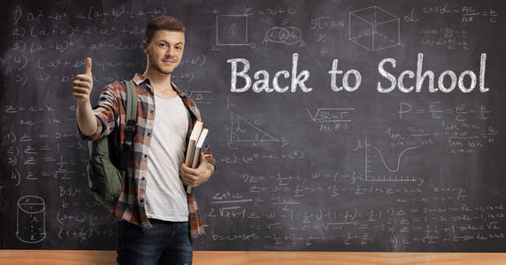 男学生拿着书站在黑板前