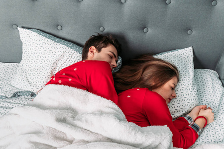 这对夫妇躺在床上，拥抱着，看上去很幸福地睡在一起。