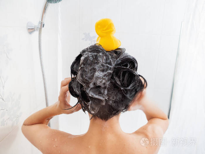 裸体短发女人洗澡那个女人用洗发水洗头白色浴室里女孩头上的黄色橡胶