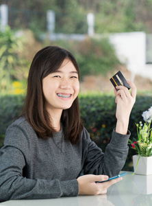 Young woman sitting showing credit card 