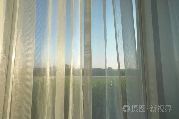 清晨的阳光透过窗上的白色窗帘