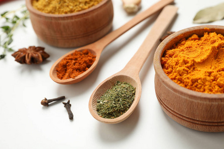 Spoons and bowls with different spices and ingredients on white 