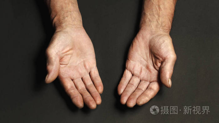 桌子上一位老人皱着皱纹的手特写了一张黑色的照片