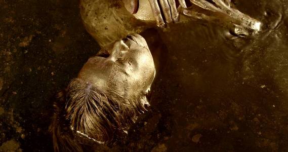 涂的金特写镜头是一个裸体,湿漉漉的黑发女人,全身涂着金色颜料,她