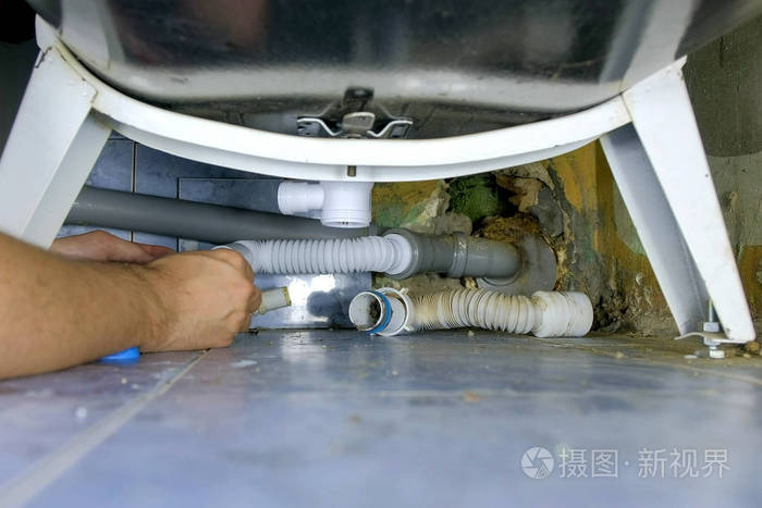 水管工在浴室的浴室里用新的管子修理替换管道