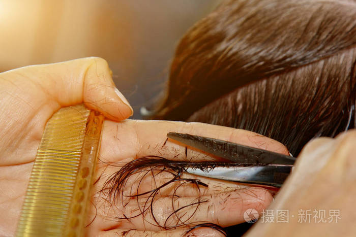 理发师的特写镜头在沙龙里剪下顾客湿棕色的头发理发