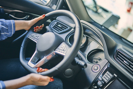 Close up female hand holding a steering wheel before purchasing 