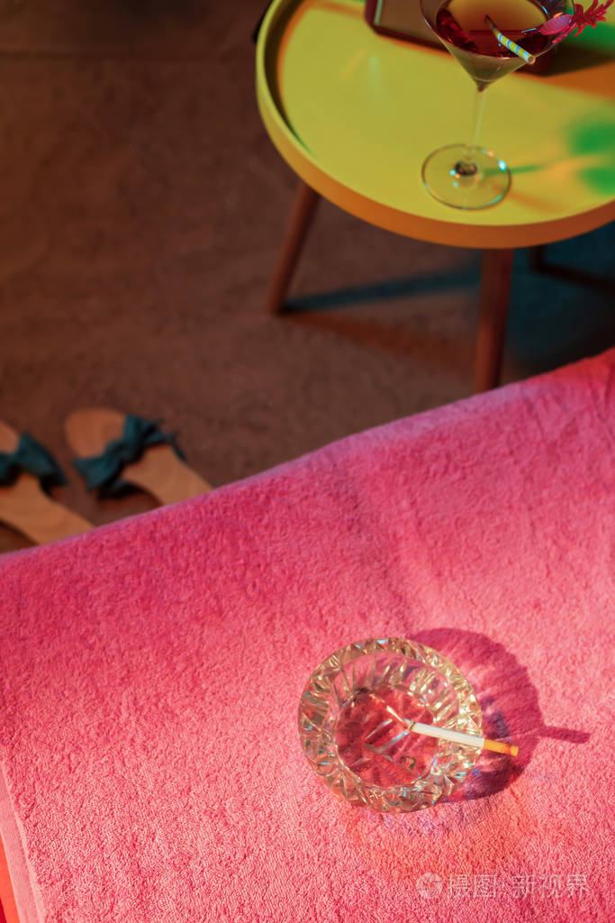 烟灰缸和燃烧的香烟在日光床上与20世纪50年代复古拉迪