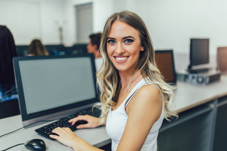 年轻漂亮的女孩在教室里用电脑工作