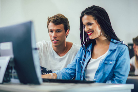 College students sitting in a classroom, using computers during 