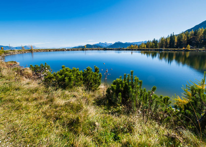 Peaceful autumn Alps mountain lake with clear transparent water 