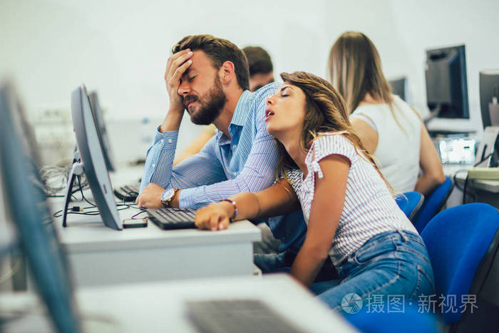 College students sitting in a classroom, using computers during 