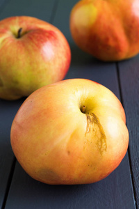 在木灰色背景特写的皮肤上有缺陷的丑陋苹果不完美,畸形的有机水果