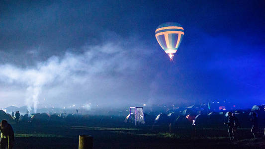 热气球在天空下壮观的卡帕多西亚上空飞行，夜晚有银河和星星带谷物