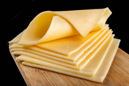 Slices of yellow cheese on a wooden board. Food from the market 