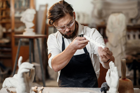 专业雕塑家手里拿着新鲜的手工石膏模具，从硅树脂模具中取出后，看着自己作品的最终成果。